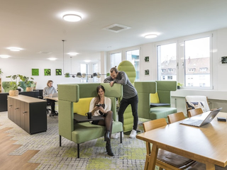 Lounge-Bereich mit zwei Personen und einer Person im Hintergrund im Coworking Space Rivvers Dortmund-Westfalenpark.